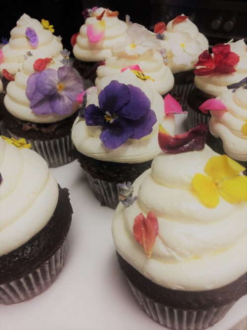 6 cupcakes with icing and flowers on top